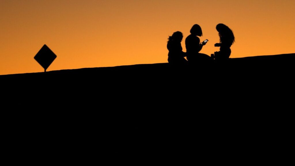 Young women look at their phones as they sit on a hillside after sun set in El Paso, Texas, U.S., June 20, 2018. (Reuters File)