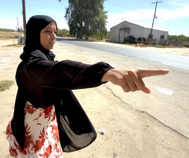 Image of a woman pointing at the site of past flooding in Pond, a Kern County community in California